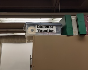A mini disaster kit located on top of a cabinet labeled 'Disaster Supplies" in a big bold font.