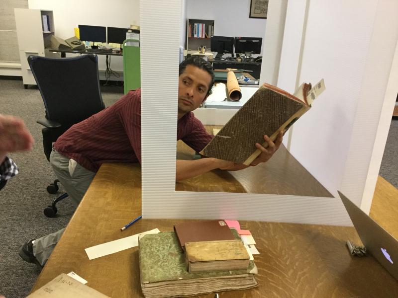 Photo of Marco Valladares Perez placing a book from the University of Illinois’s Rare Book and Manuscript Library in a planning area.