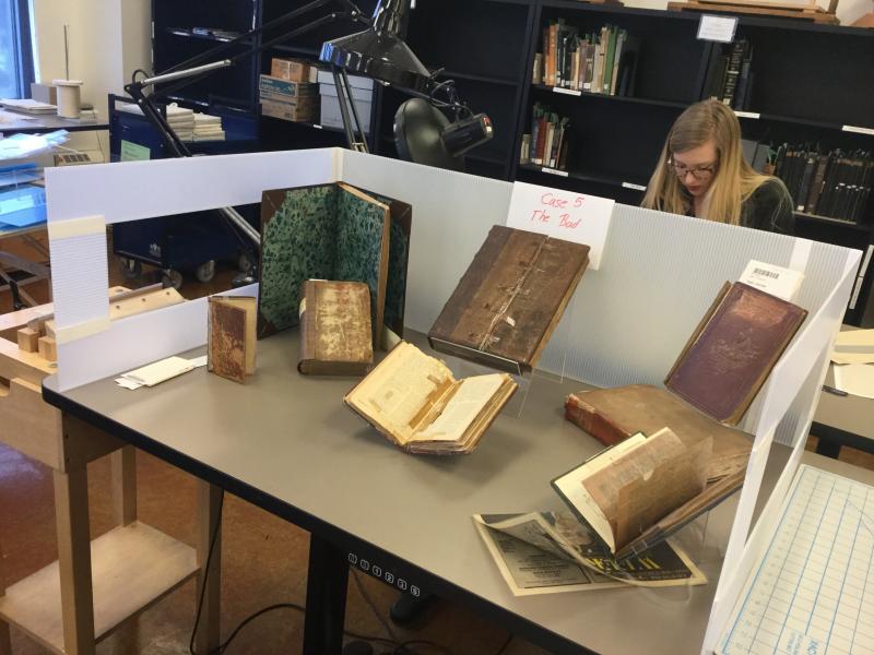 Photo of various books with bad conservation treatments arranged for “case 5” in the Rare Book and Manuscript Library